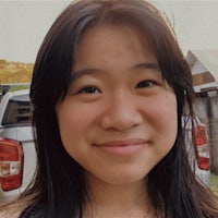 a young asian woman smiling in front of a truck